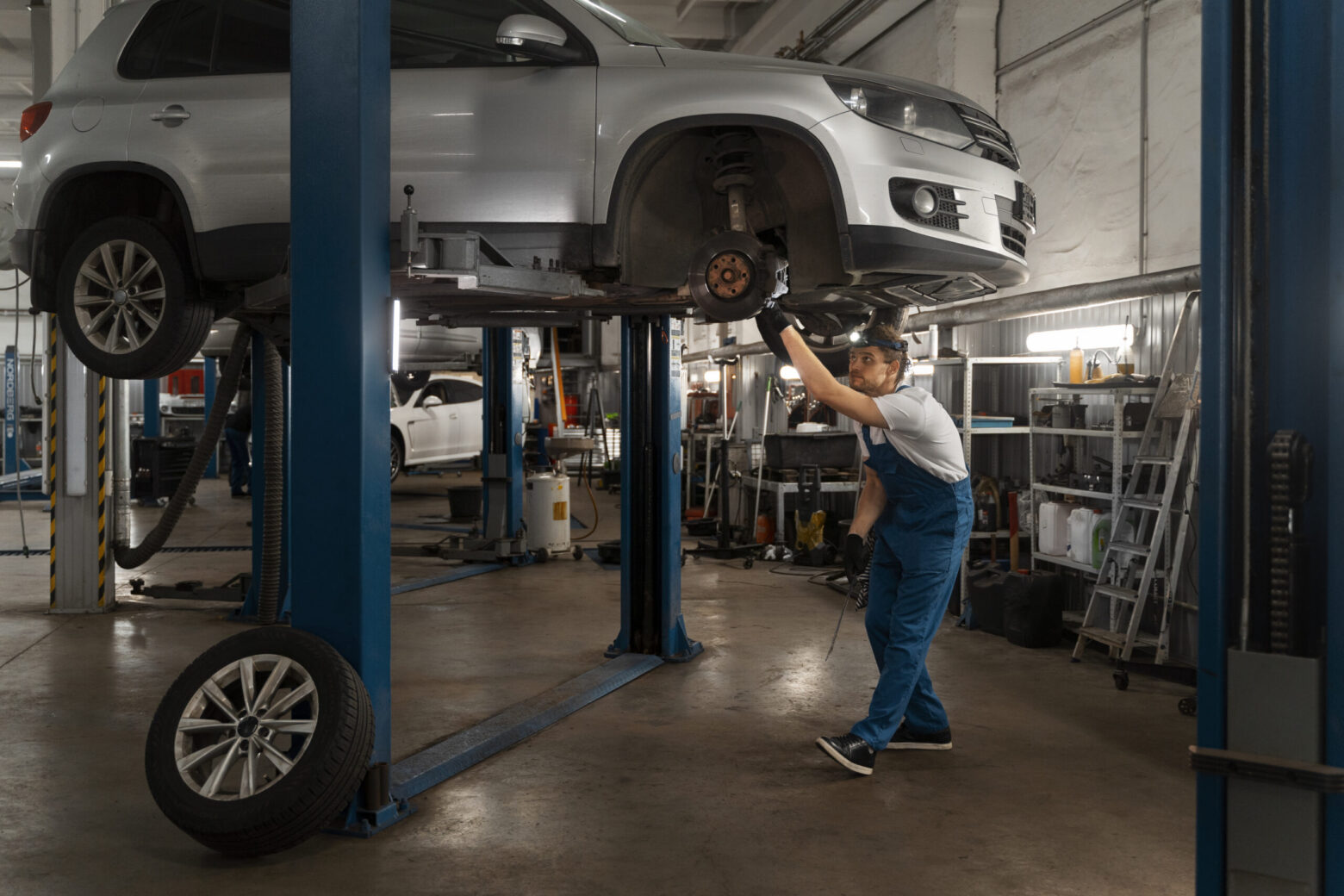 Mechanic inspecting raised silver SUV with wheel removed